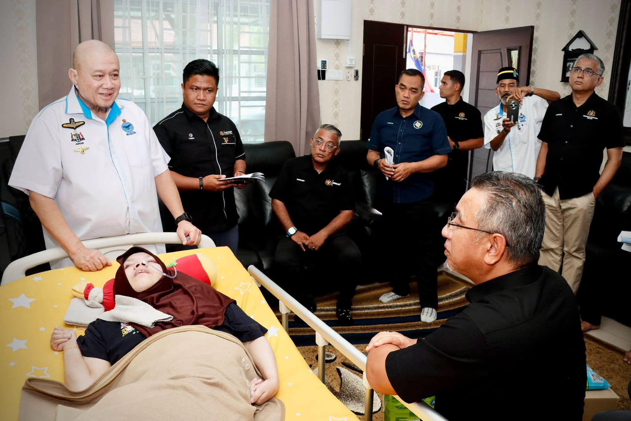 Rombongan melawat seorang pesakit yang sedang berehat di katil.